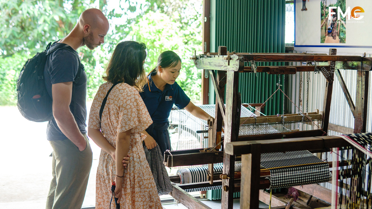A tour guide is showing how the loom work to the tourists