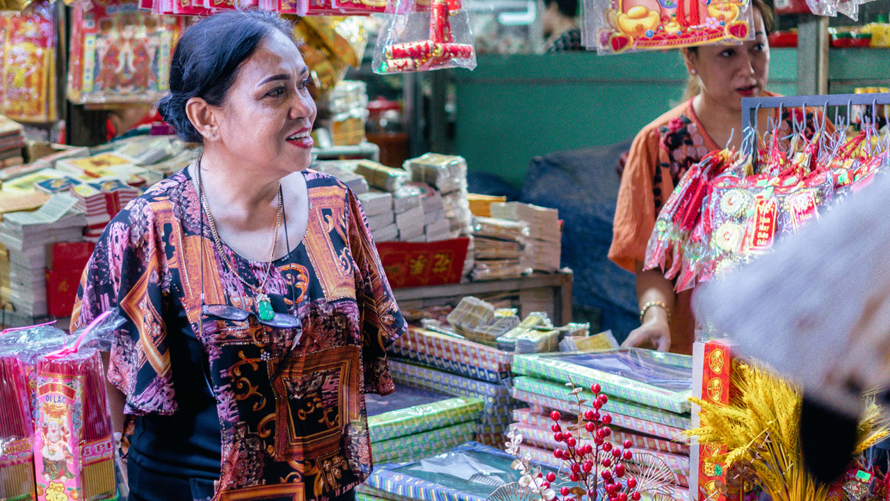 Smiling sales woman welcomes customers to buy goods at a Vietnamese market