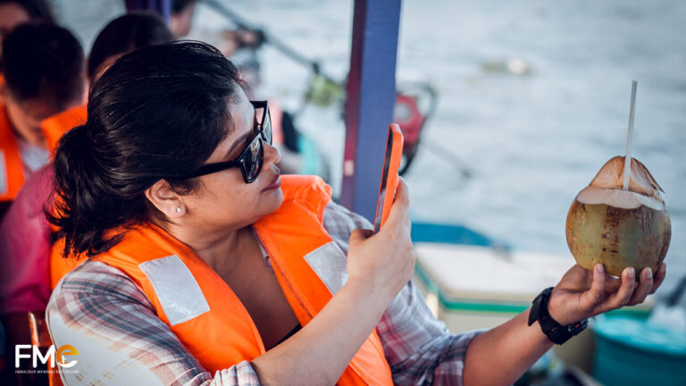 Tourist taking photos of her coconut drink at Cai Rang floating market