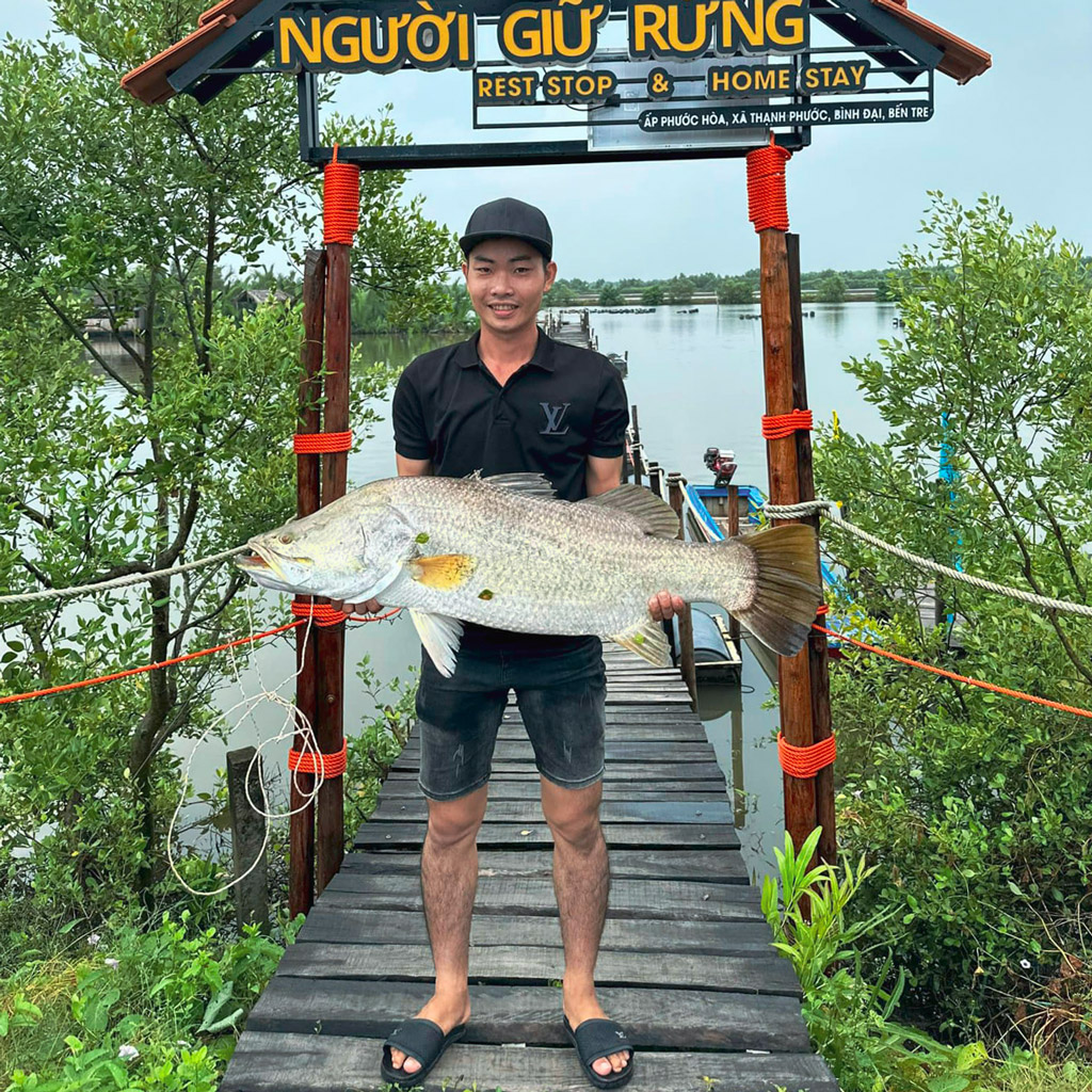 Tourist with a big fish just caught at Nguoi Giu Rung eco-tourism area