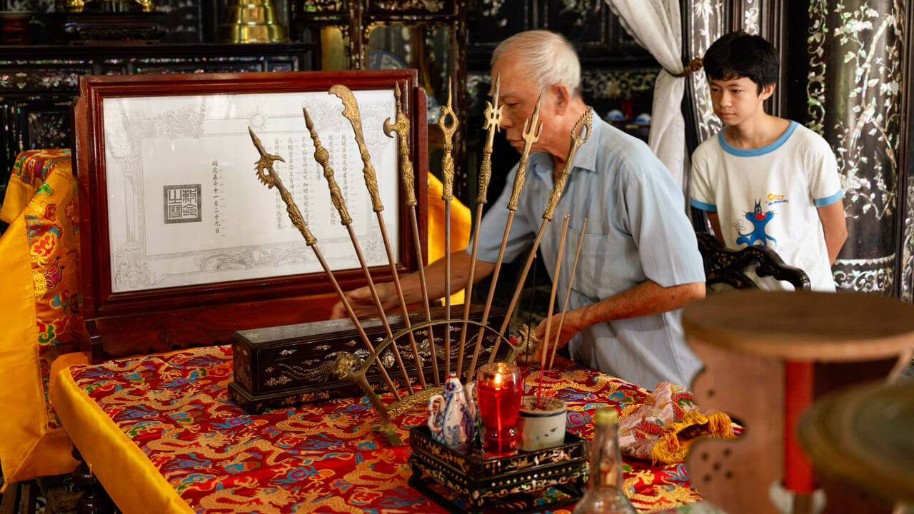 An elderly man showcasing ancestral treasures at Le Cong Ancestral House, preserving family heritage