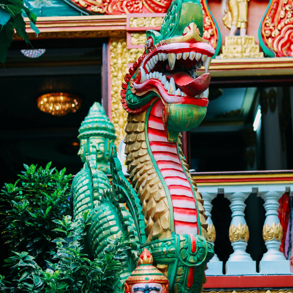 A lifelike sculpture of the Naga snake god guards the entrance to the Pitu Khosa Rangsay Temple, symbolizing protection and power