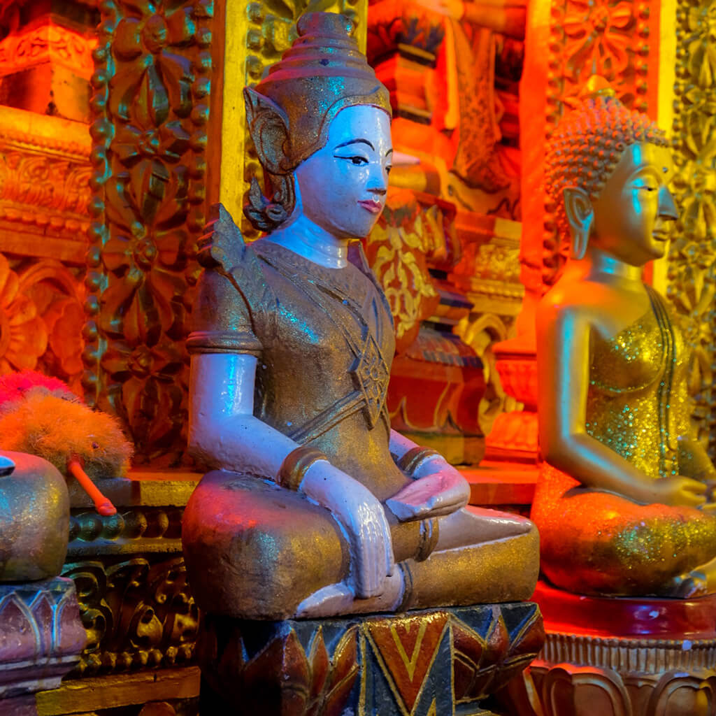 Golden Buddha statues illuminated by vibrant colors in a Vietnamese temple