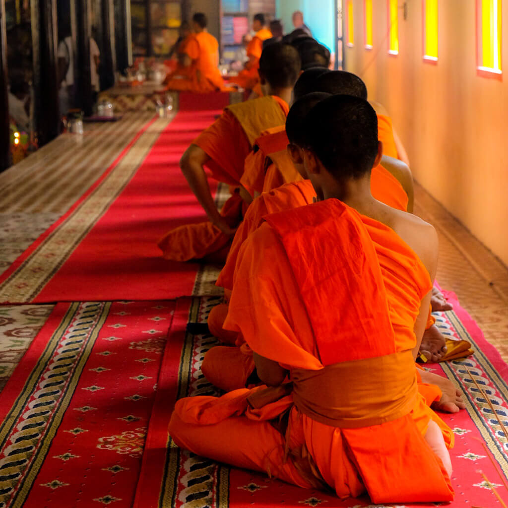 Monks sitting in a prayer line during a ceremony in a Vietnamese temple