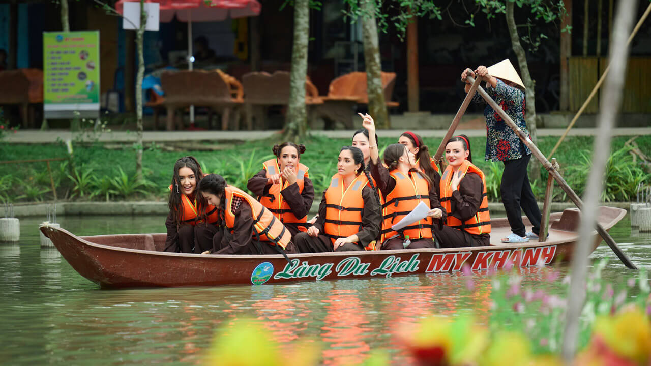 A group of tourists on a traditional boat ride at My Khanh Tourism Village, immersing themselves in the serene beauty of the Mekong Delta waterways