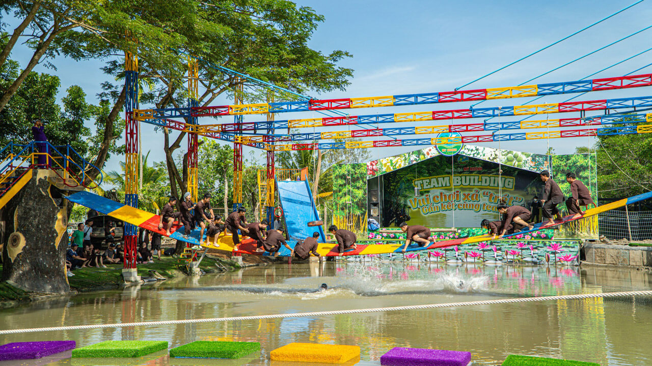 Groups participating in dynamic team-building activities at My Khanh Tourism Village, featuring obstacle courses and lively challenges