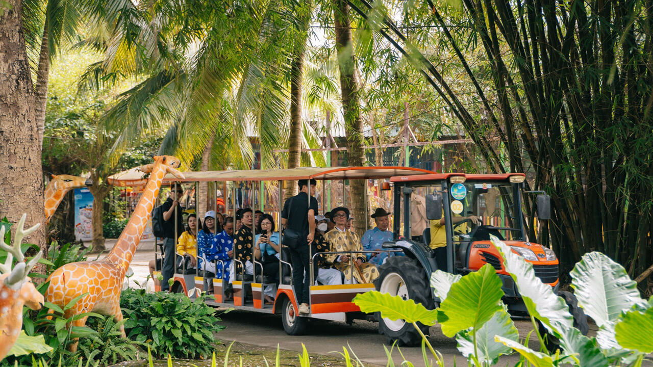 Guests enjoying an electric train ride through the scenic and lush landscapes of My Khanh Tourism Village, perfect for sightseeing in Can Tho