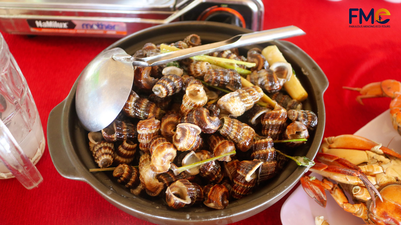 A bowl of sautéed snails seasoned with lemongrass and spices, served hot at Dung Islet in the Mekong Delta