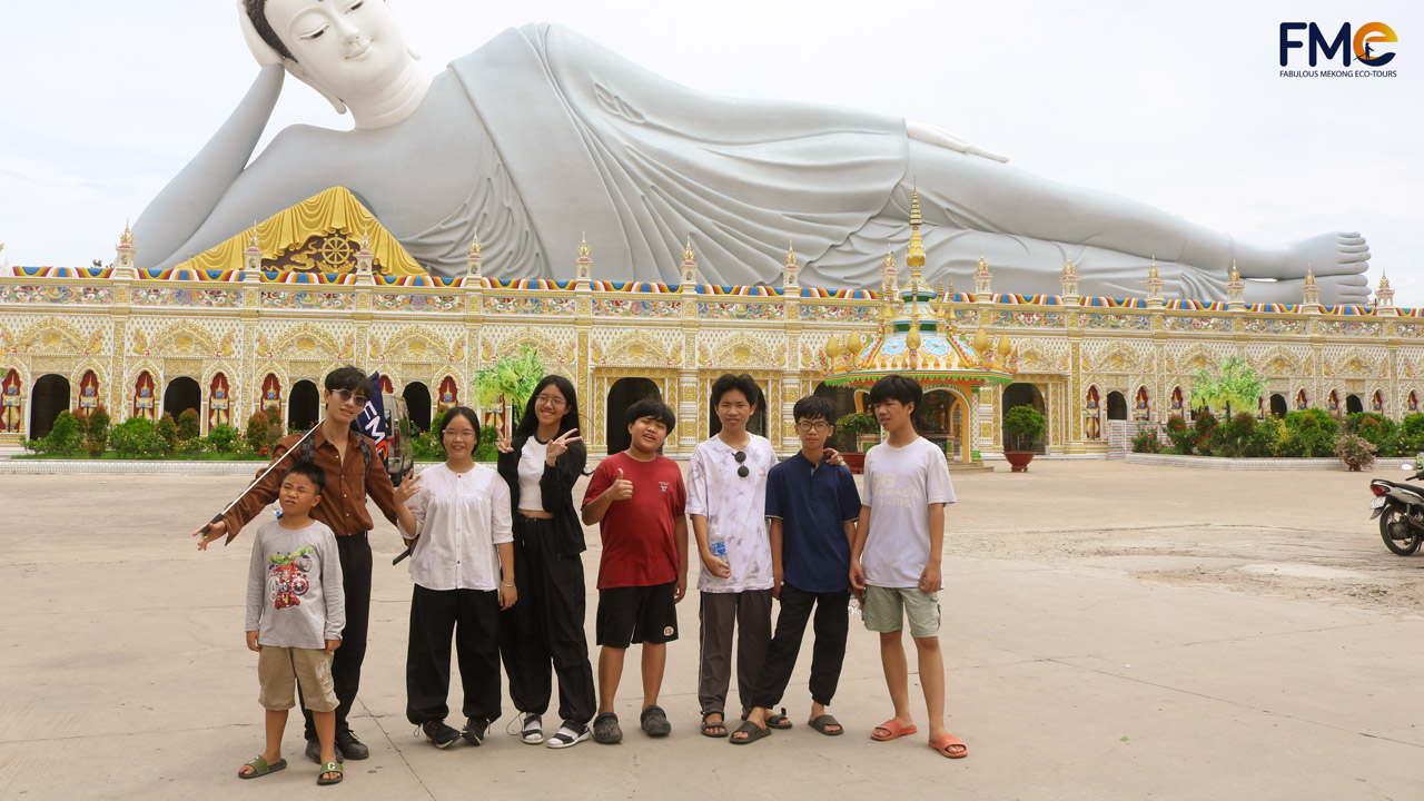 Tour group in front of the Reclining Buddha statue at Som Rong Pagoda, a famous spiritual destination in Soc Trang