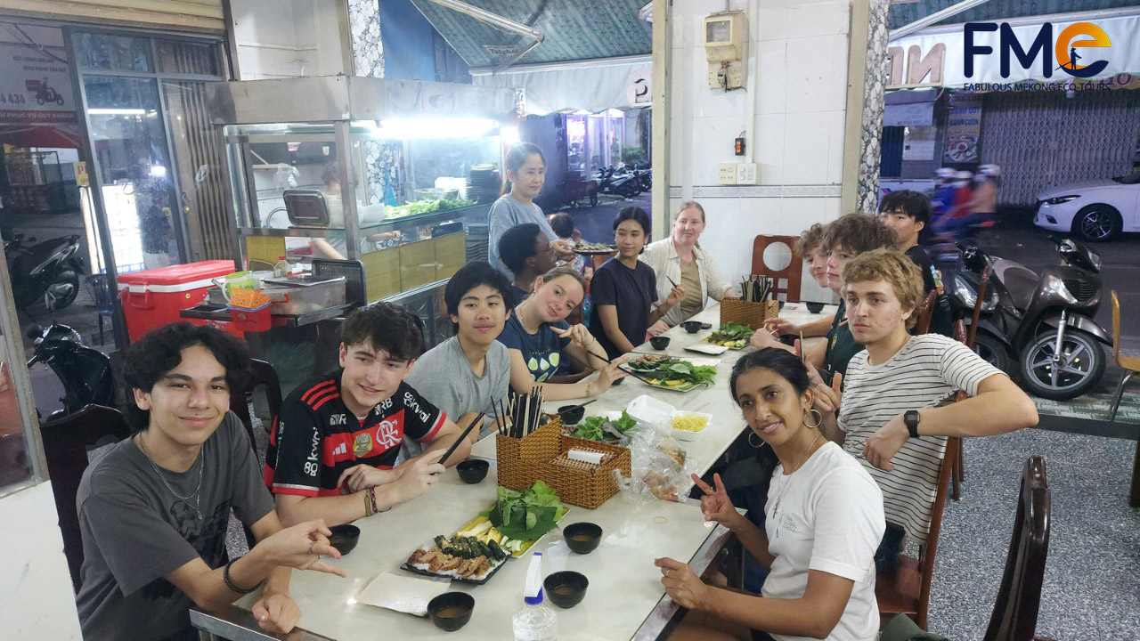 Group of students enjoying Vietnamese dishes while sharing cultural experiences at a traditional eatery in Can Tho