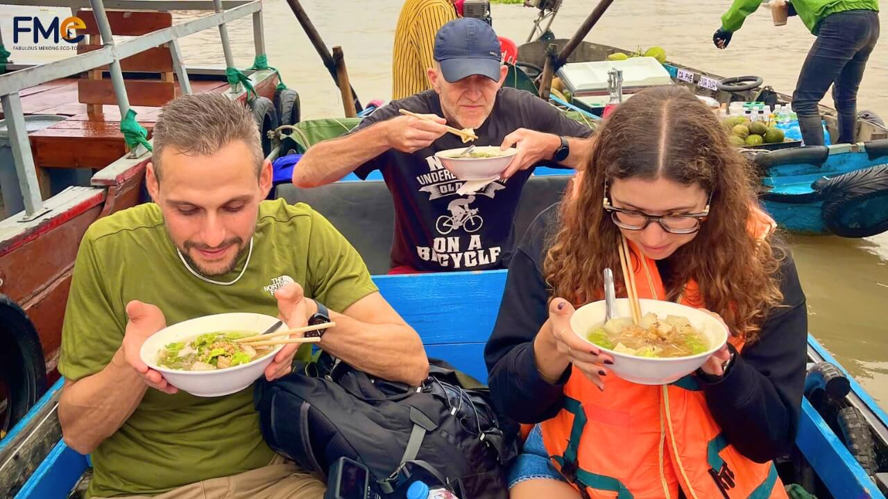Guests enjoy breakfast on a boat at Cai Rang Floating Market