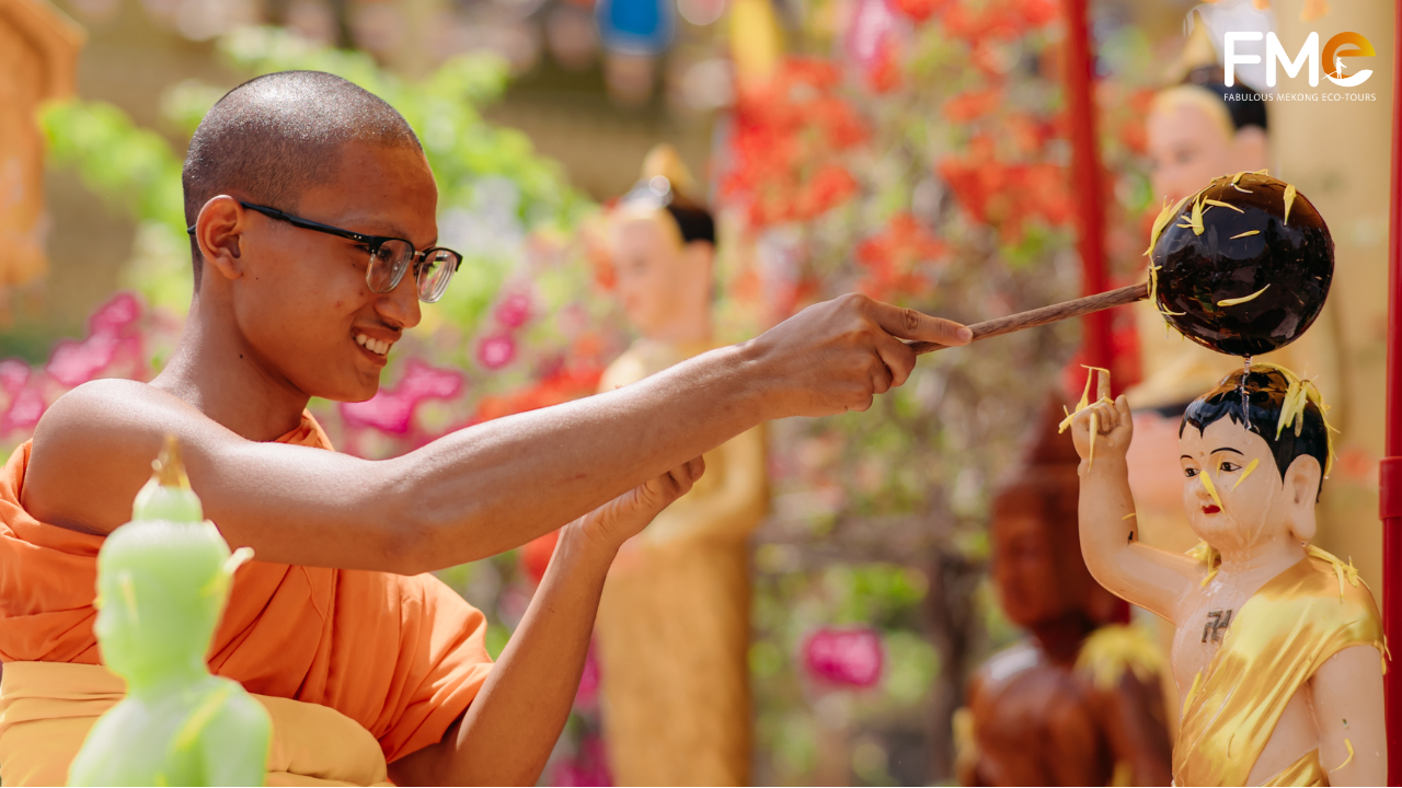 A young monk using a floral-scented water dipper to bathe a statue of the baby Buddha, a solemn ritual during Chol Chnam Thmay 2026.
