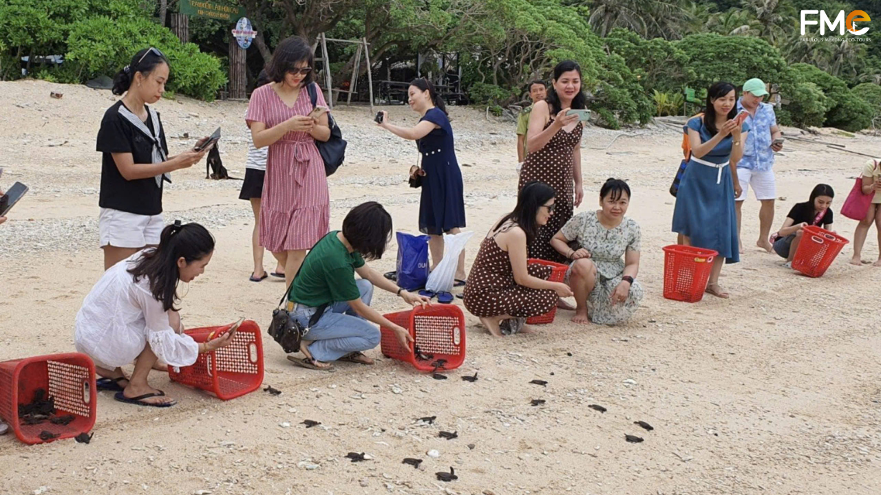 A traveler with a backpack points towards a distant island in Con Dao, Vietnam, signaling the start of sea turtle nesting season with FME Travel.