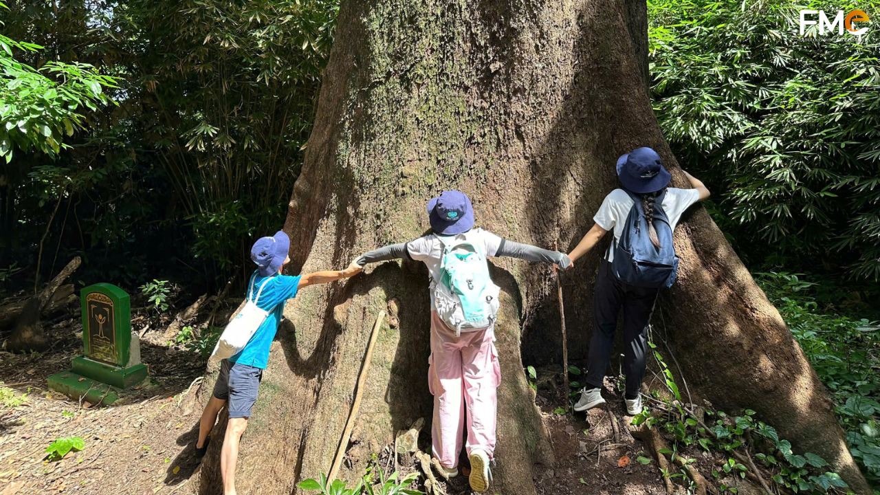 FME Travel tour group posing happily on a scenic coastal path overlooking the turquoise waters and distant islands of Con Dao, Vietnam.