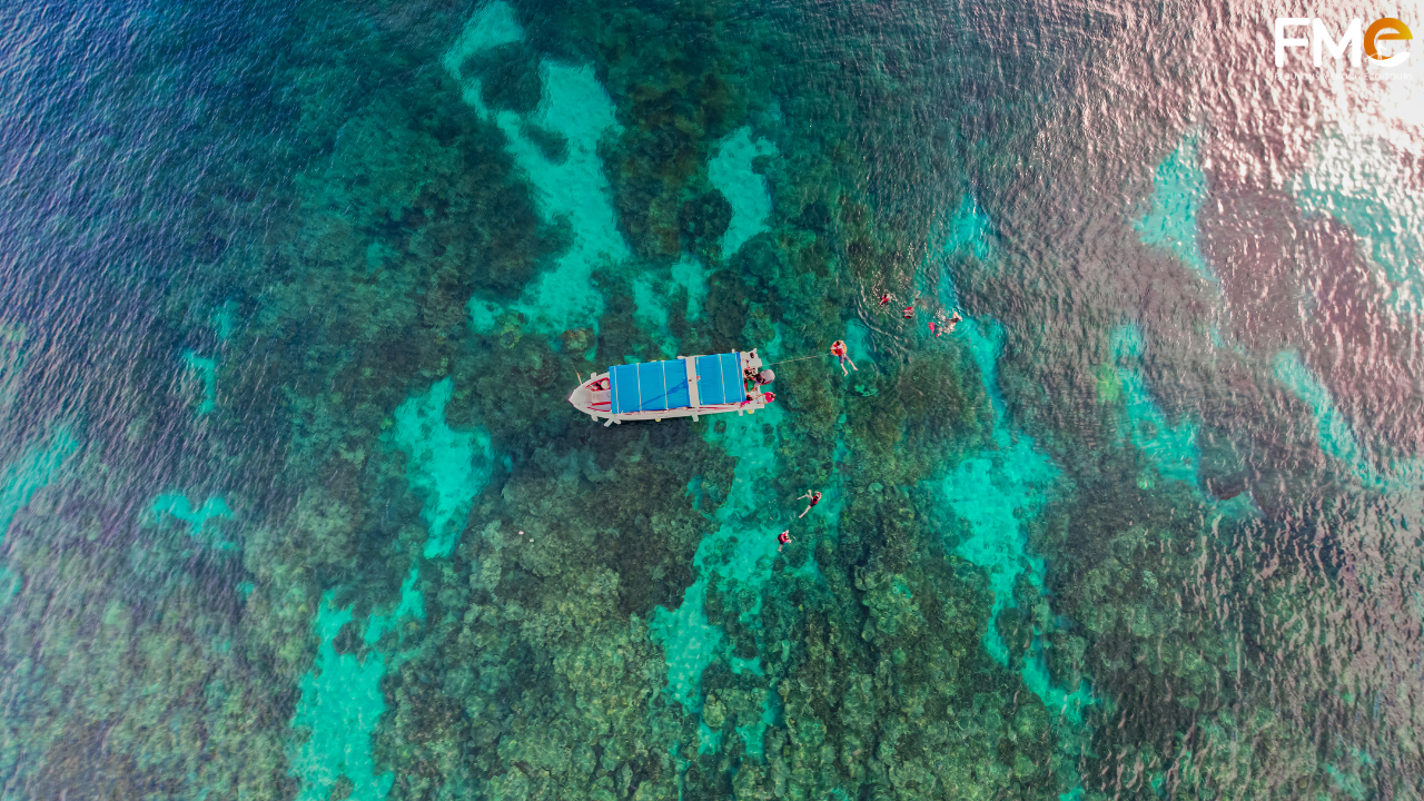 Aerial view of a private boat tour exploring crystal clear turquoise waters and coral reefs, defining the new luxury of exclusivity in Con Dao.